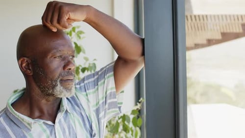 Senior Man Looks Pensively Out Home Window