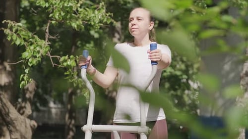 Woman Working Out on Outdoor Exercise Equipment in the Park