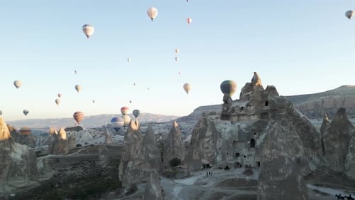 Aerial view of cave homes with hot air balloons in Cappadocia, Turkey.