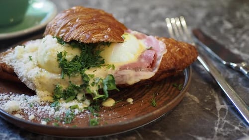 A Truly Delicious Croissant Sandwich Filled with Ham and Topped with a Poached Egg for Breakfast