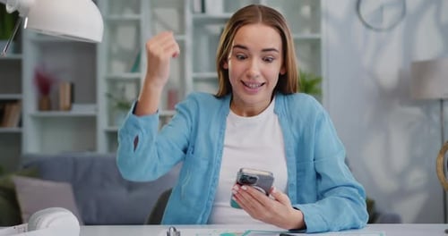 Closeup joyful girl reading good news, enjoying success on mobile phone in home office. Surprised