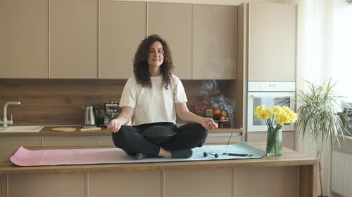 Woman Meditating on Kitchen Island With Incense