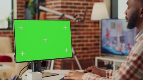 Man Works at Desk on Computer with Green Screen