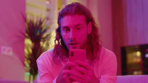Man Looking at Phone in a Neon Room