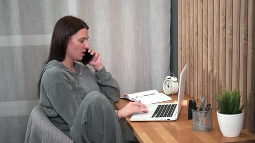 Woman Working at Laptop and Talking on Phone