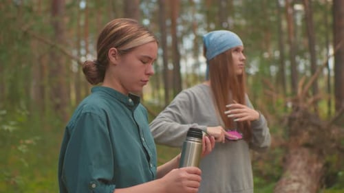 Sisters Enjoy Peaceful Break in Forest with Thermos and Hair Care