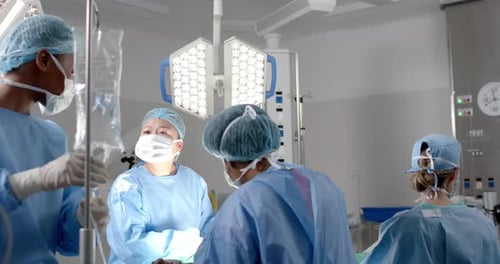 Diverse female surgeons operating on patient in operating theatre, slow motion