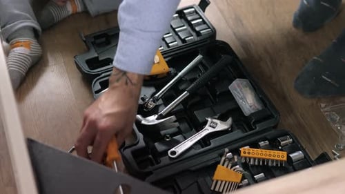 Child and Adult Sorting Through Toolbox on Floor
