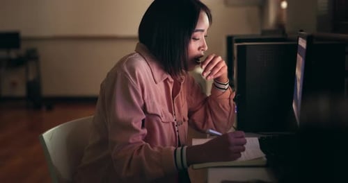 Student, woman and tired on computer for night research, studying and writing notes for university