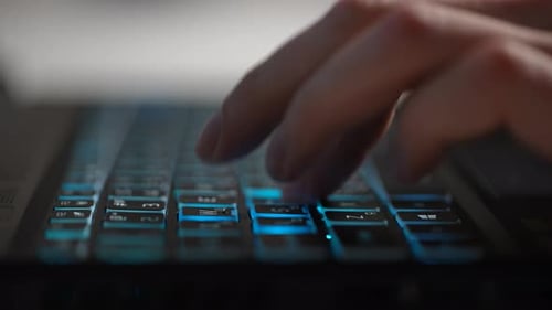 Closeup Hands of Unrecognizable Male Gamer Playing Video Game on Laptop with Glowing Rgb Keyboard
