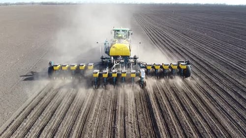 Tractor with yellow seeder working on the field in Ukraine OA Lexa