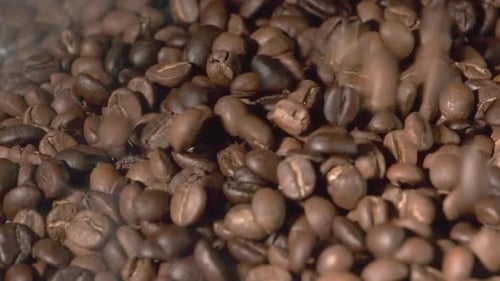 Zeitlupe fallender gerösteter Kaffeebohnen.