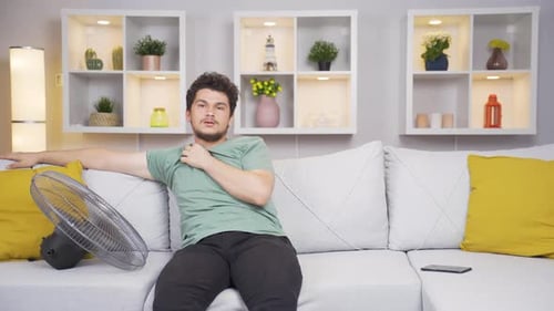The man using the fan is overwhelmed by the heat.