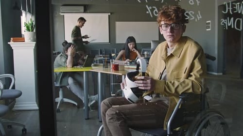 Portrait of Young IT Specialist in Wheelchair Holding VR Headset in Office