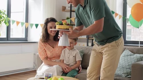 Family celebrating birthday together with cake in living room