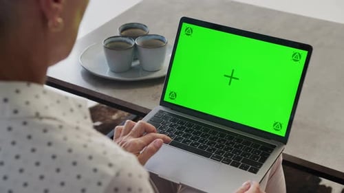 Person Using Laptop with Green Screen at Home