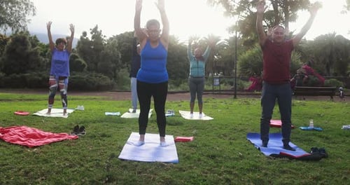 Multiracial senior people doing yoga exercises outdoor with city park in background