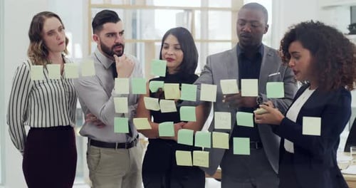 4k video footage of a group of businesspeople brainstorming with notes on a glass wall in an office