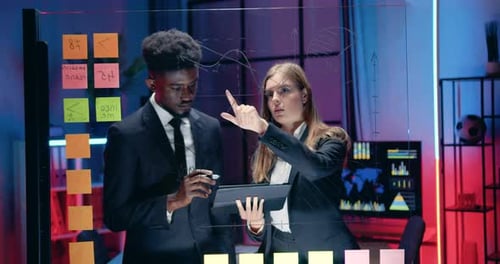 Close up of man and woman business people which working near glass wall with information from tablet