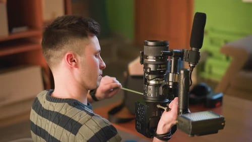 Young Adult Adjusting Professional Video Camera in Living Room