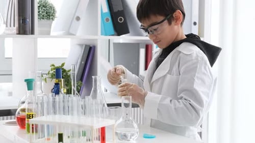 Boy in Lab Mixing Chemicals in Beakers