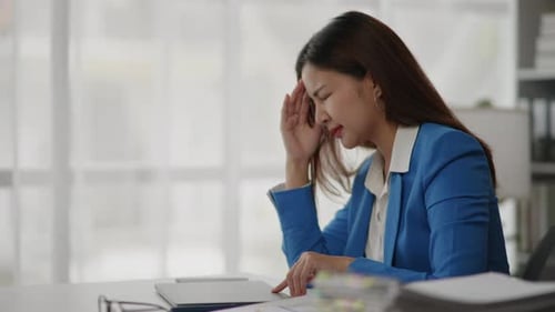 Businesswoman is seriously stressed working feel eye ache headache due to office syndrome.