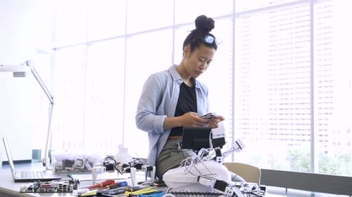 Ingeniera con teléfono inteligente trabajando en un laboratorio de robótica