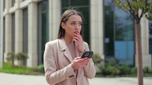 Worried Woman Using Phone on Urban Street
