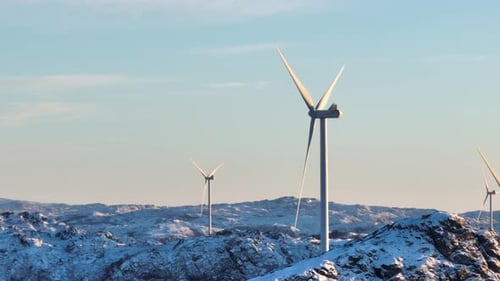 Aerial View of Wind Turbines Array on Top of Snow Capped Mountain Hills on Sunny Winter Day, Drone S