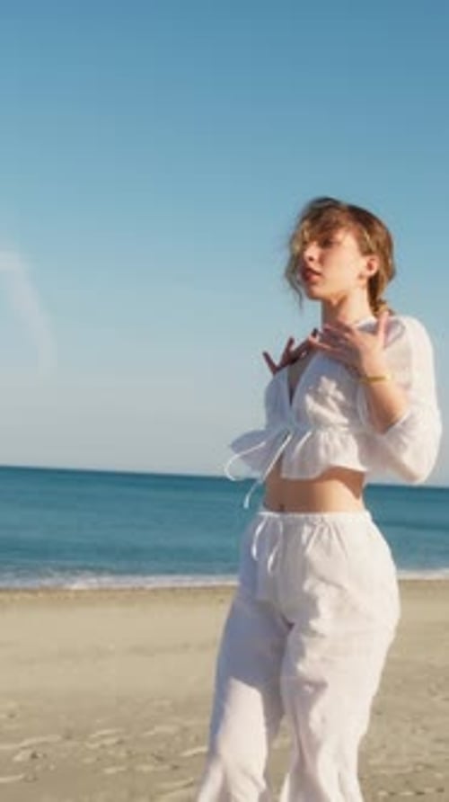 Blonde Girl With White Dress Dances On The Beach In Summer Near The Sea