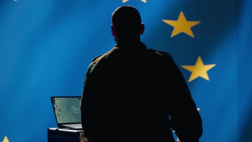 Man Using Laptop in Front of EU Flag