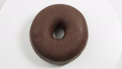 Rotating dark vegetarian donut isolated on white background.