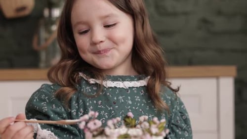 Happy Little Girl Eating Cake at Home