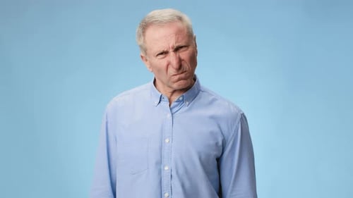 Man Expressing Anger With Clenched Fist Against a Plain Background in Video Footage