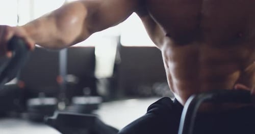 Sexy gym man training on exercise bike with six pack abs, strong body and muscle.