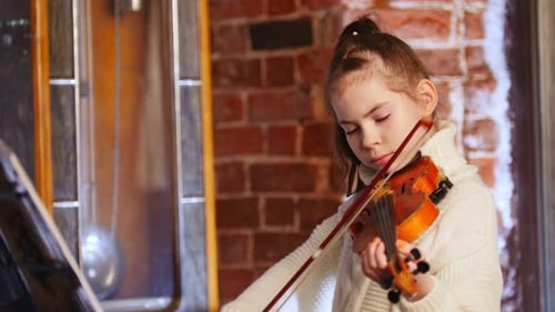 Focused Young Girl Plays Violin in Cozy Room