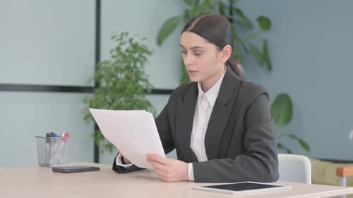 Woman Reviews Documents at Desk in Office