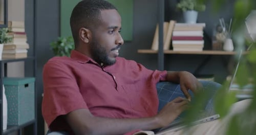 Man Works on Laptop From Couch At Home