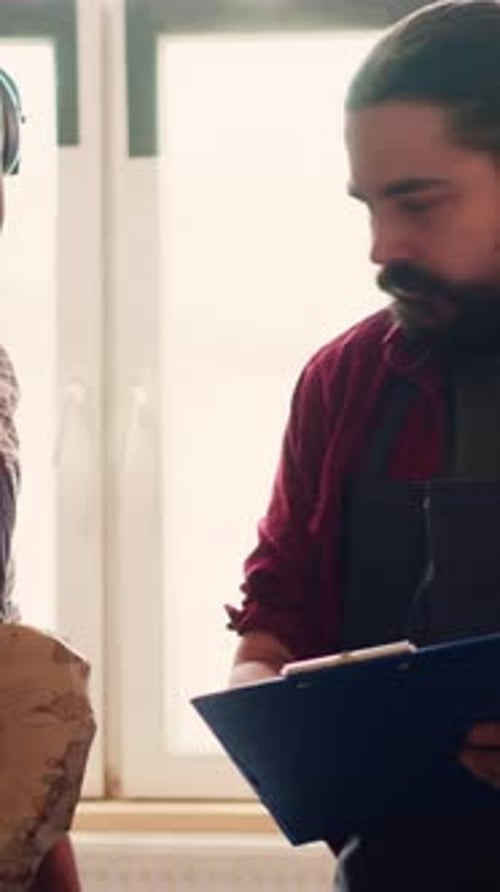 Vertical Video Manufacturer and Apprentice Reading Furniture Assembly Schematics in Studio