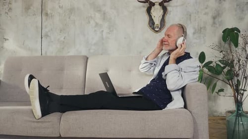 Man Relaxing on Couch Listening to Music