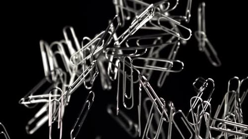Paper Clips Falling Slowly On Black Background