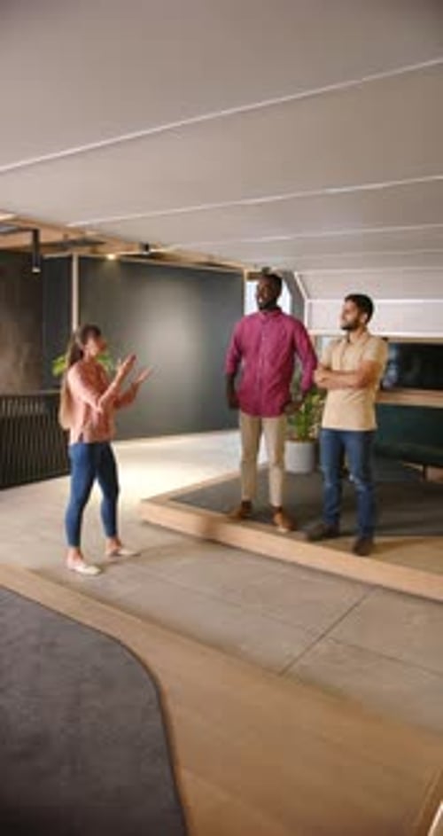 Vertical video: Discussing project, diverse business team standing and talking in modern office