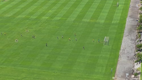 Soccer team training on lush green pitch aerial view