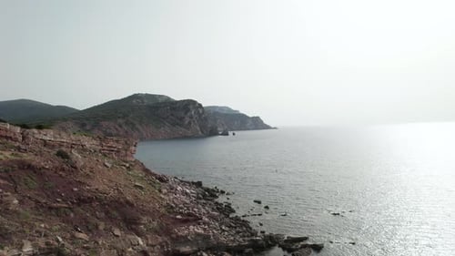 Aerial view drone over red sand sea cliff with an ancient tower in Sardinia, Italy, Penisola di Stin