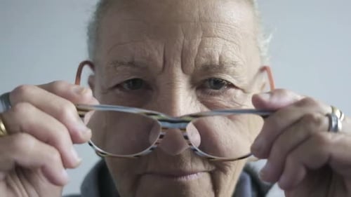 close up elder senior woman portrait wearing glasses in slow motion