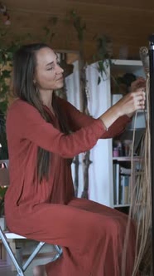 woman in dress weaves macrame at home