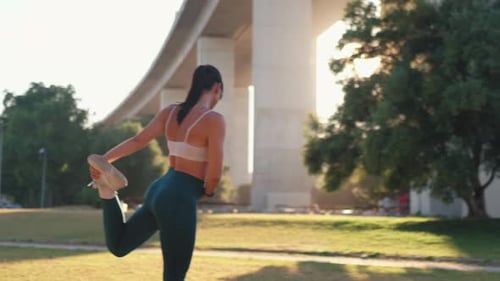 Fit Woman Stretching at Park During Sunrise