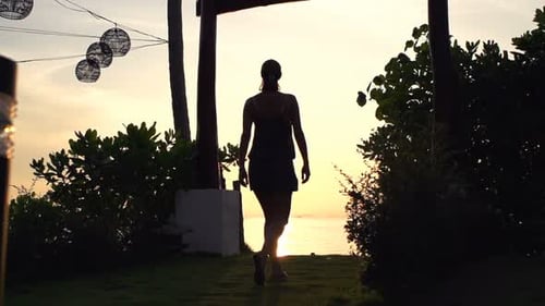 Woman walking in golden garden during summer sunset in super slow motion