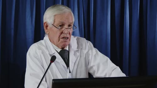 Mature Adult in Lab Coat Speaks at Podium
