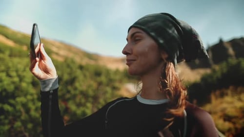 Smiling Woman Uses Phone in Mountain Landscape